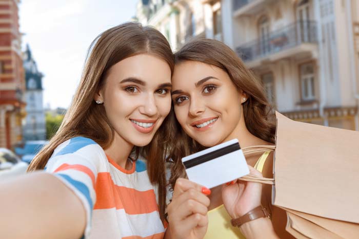 Two young ladies taking a selfie, holding a credit card